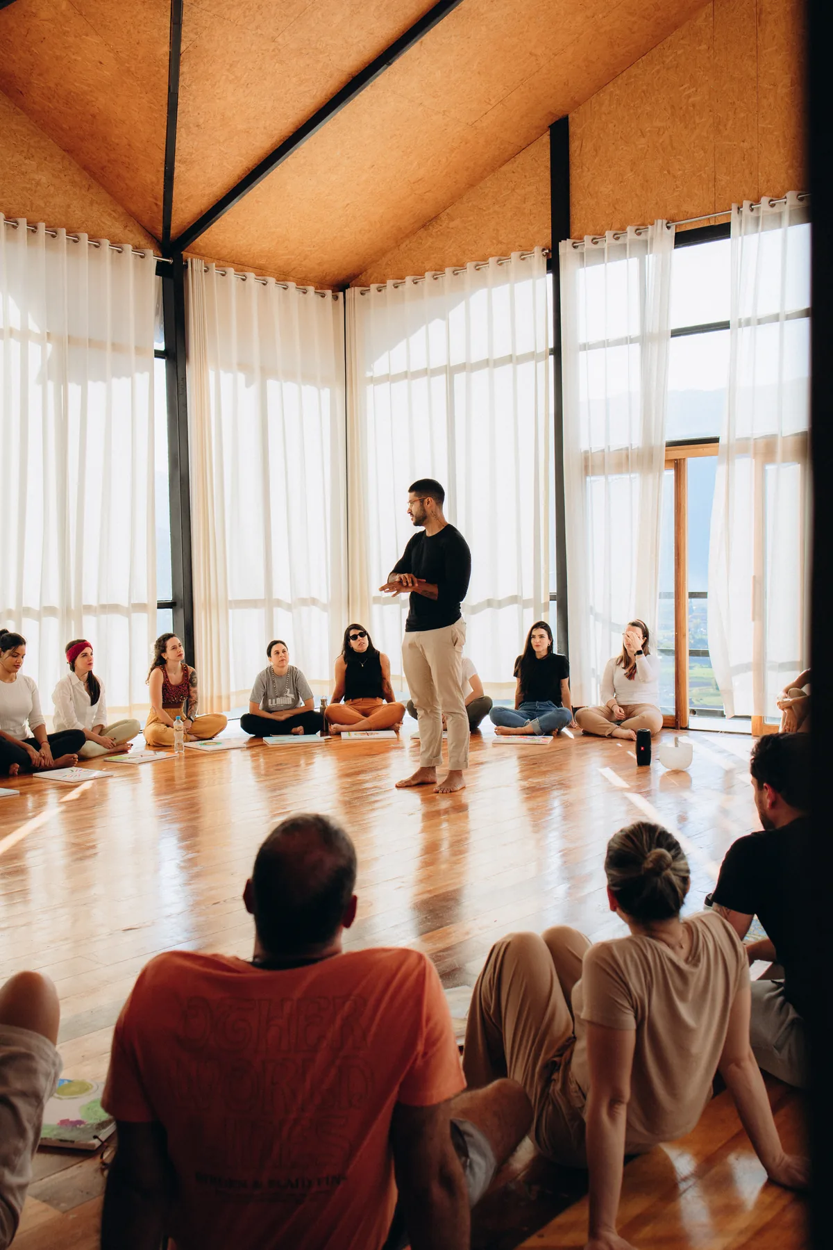 Participante em meditação ao lado de fogo cerimonial sob cobertura de palha
