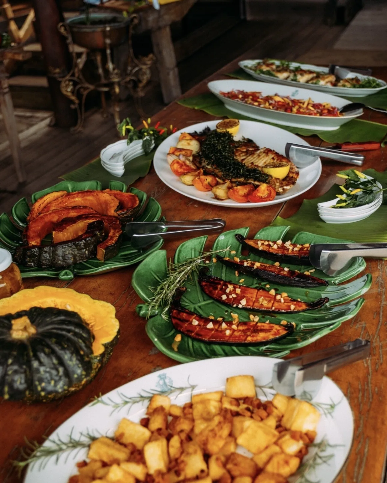 Mesa farta com gastronomia pantaneira, peixe grelhado, abóbora e mandioca em folhas de bananeira
