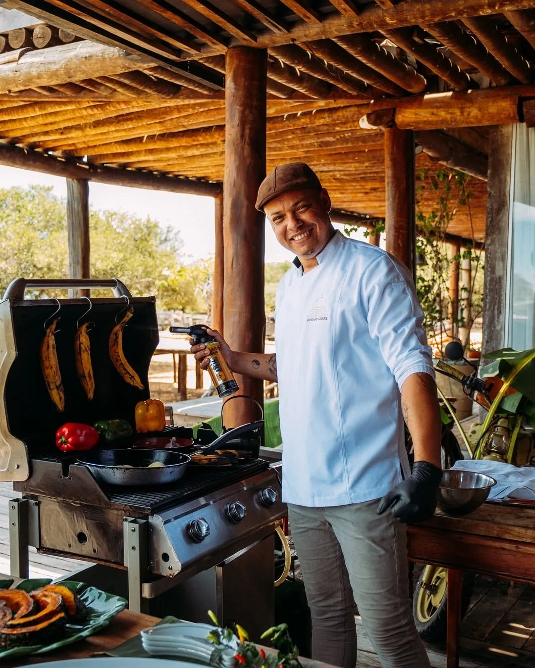 Chef sorrindo enquanto prepara gastronomia pantaneira na cozinha aberta da pousada